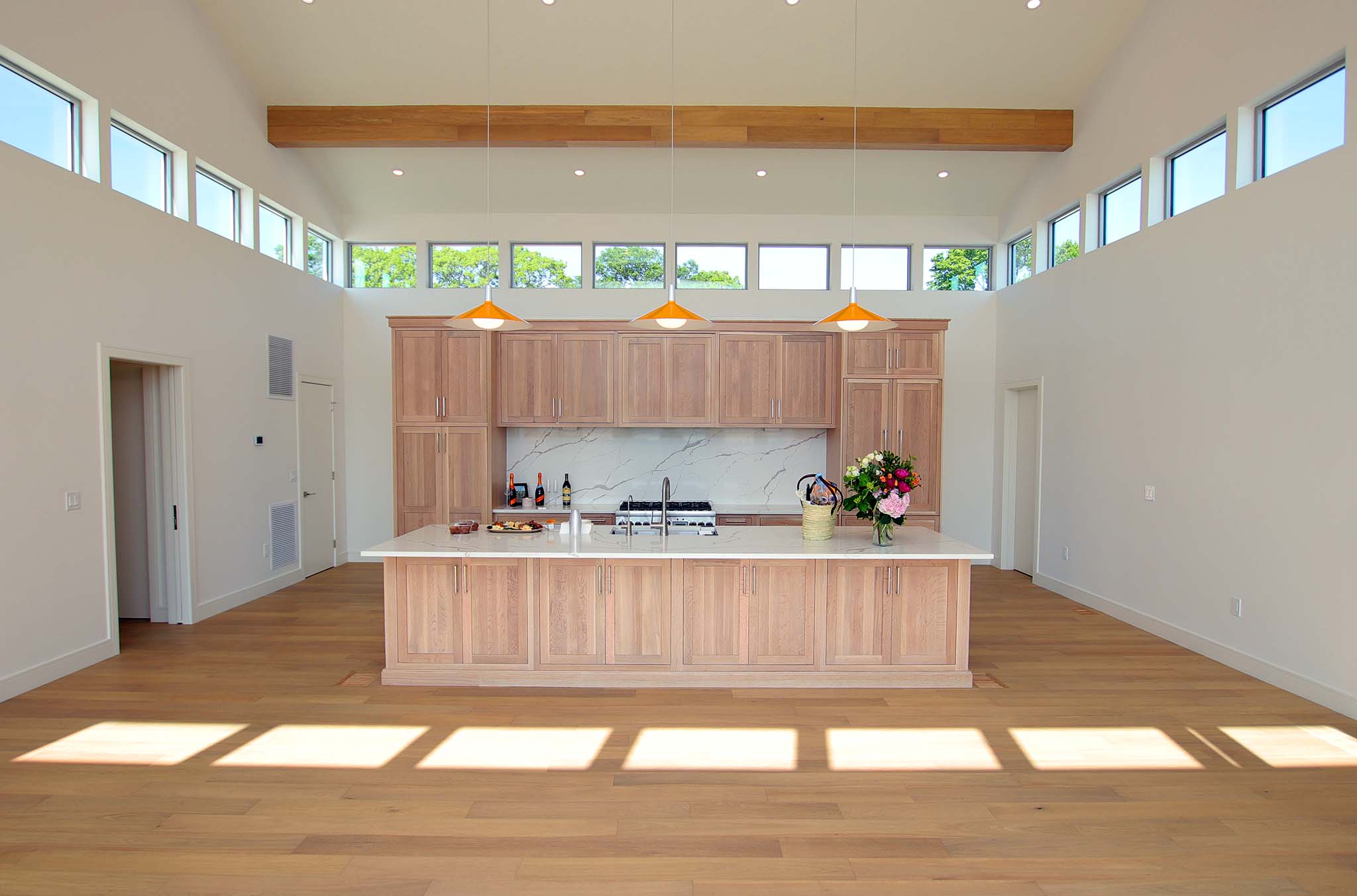 Custom coastal modern kitchen with high vaulted ceilings and clerestory windows, prioritizing flow and natural light.