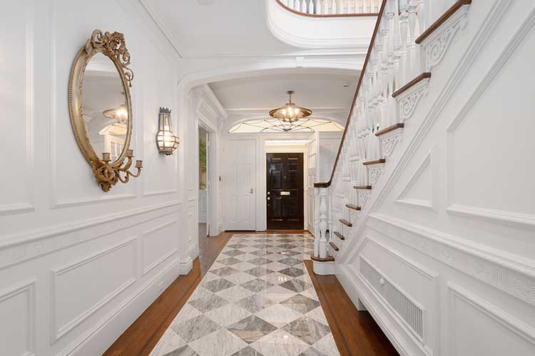 Grand entryway renovation featuring a classic black and white marble checkerboard floor and restored curved staircase.