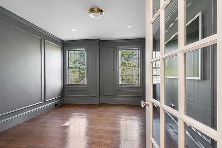 A quiet, renovated bedroom or study space in a historic Providence home, featuring grey walls and restored hardwood floors.