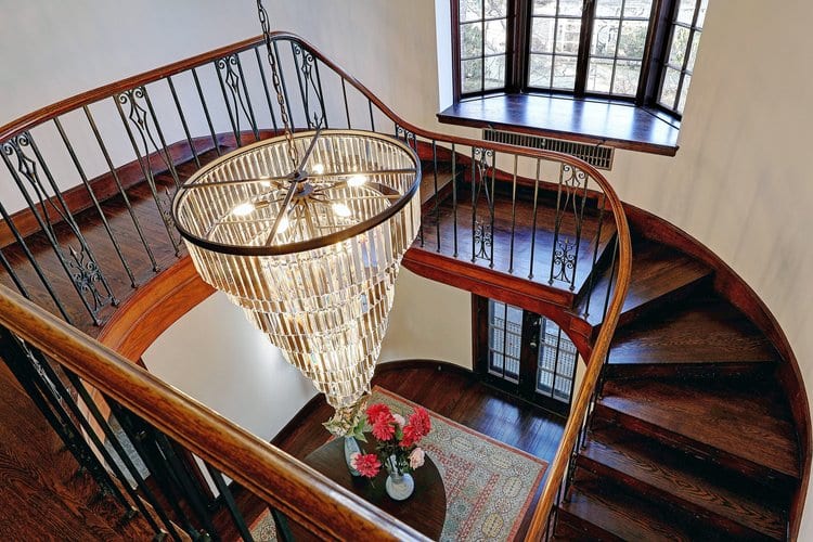 Dramatic spiral staircase with original ironwork and wood railing, a centerpiece of this East Side historic renovation.