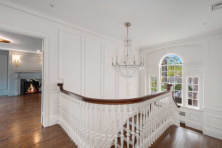 Bright and airy upper staircase landing featuring original white railings and historic architectural details.