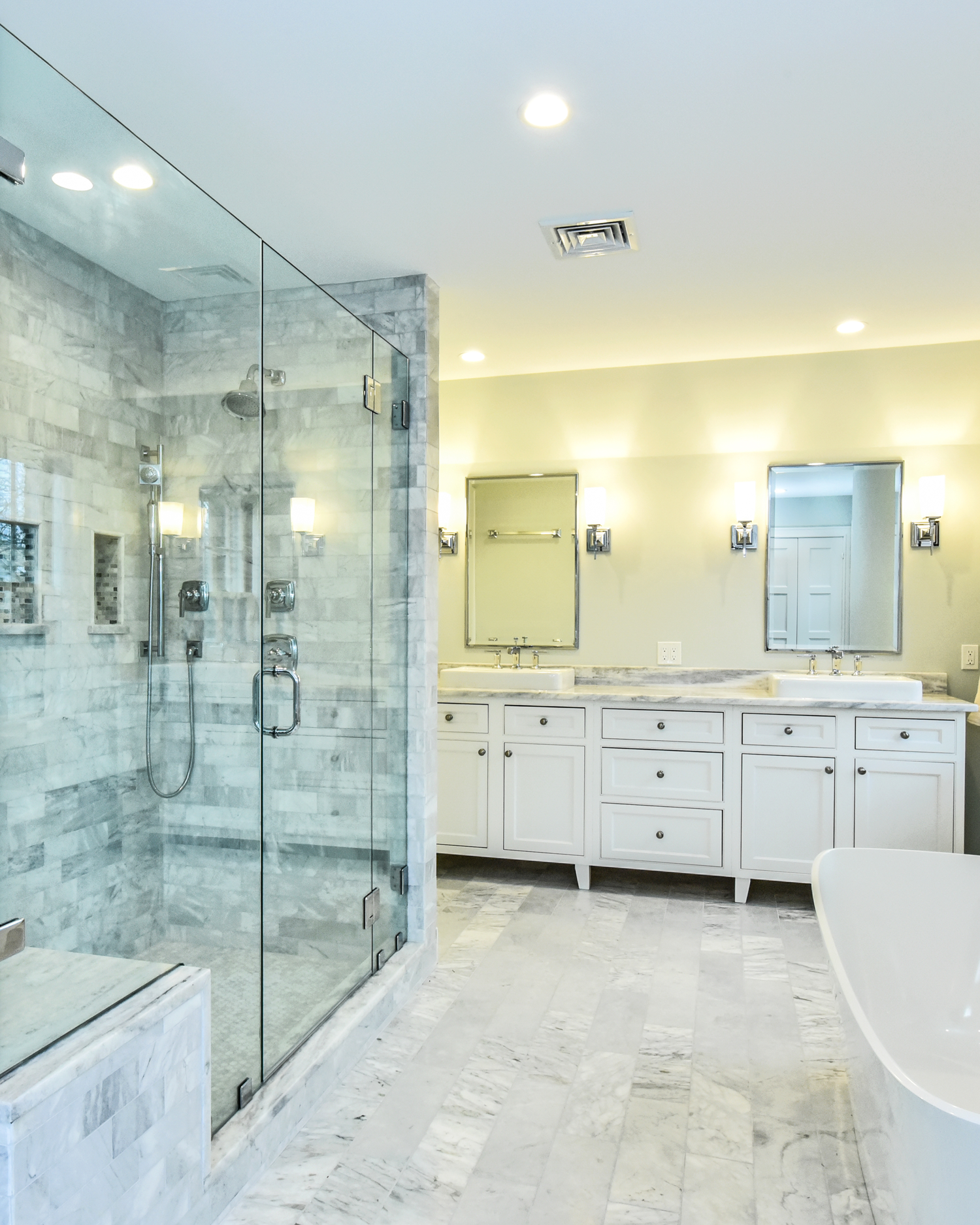 High-end bathroom renovation featuring a large glass-enclosed marble shower and custom double vanity.