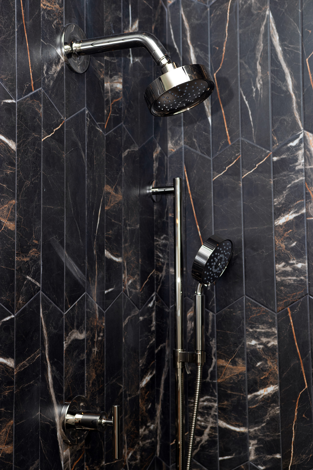 Vertical view of a custom walk-in shower with dark tiling, contrasting beautifully with the home's light coastal palette.