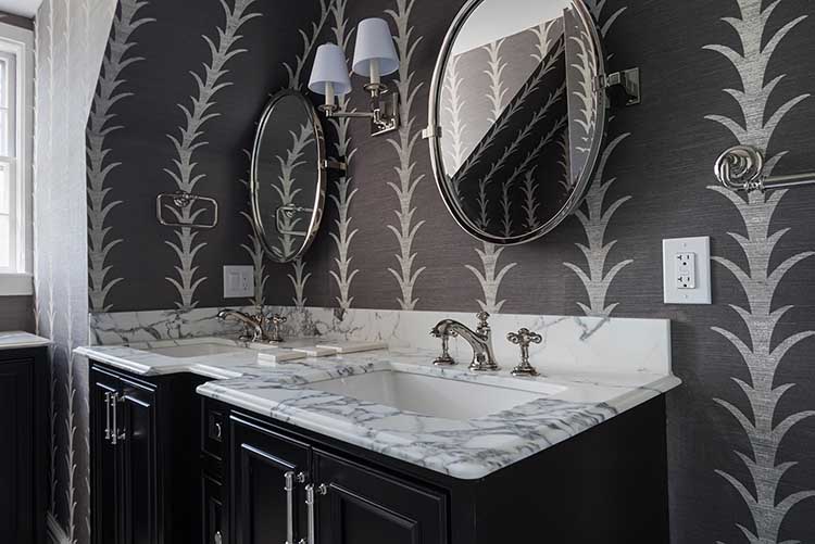 Sophisticated powder room design featuring dark patterned wallpaper and a custom marble vanity.
