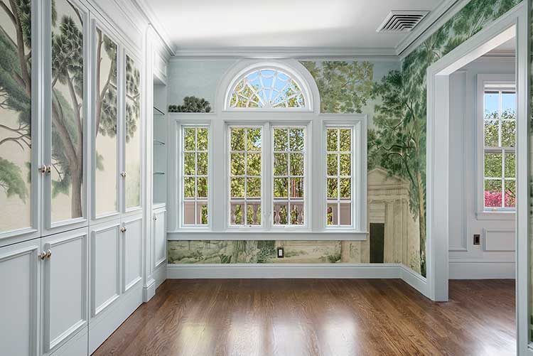 A sun-drenched solarium addition featuring scenic wallpaper murals and custom millwork, created by removing an old back staircase.