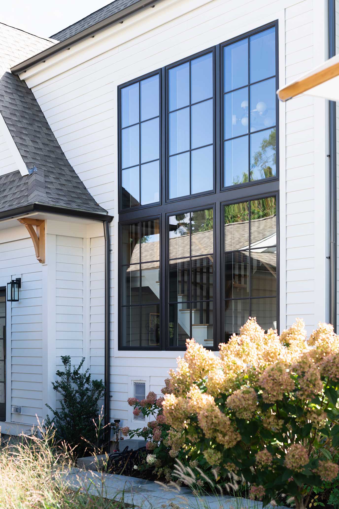 Exterior view of a custom modern coastal home in East Greenwich, RI, featuring white siding and black window frames.