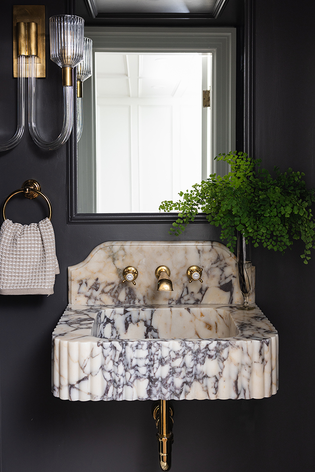 Dramatic powder room featuring a custom floating marble vanity with an integrated sink and dark moody walls.