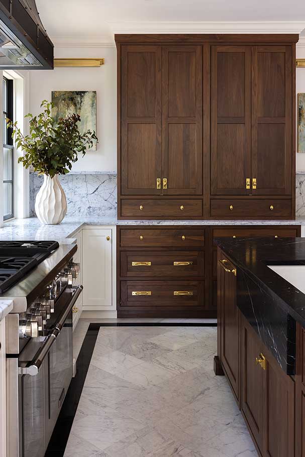 lose-up of rich walnut kitchen cabinetry with custom brass hardware, showcasing the craftsmanship of this historic renovation.