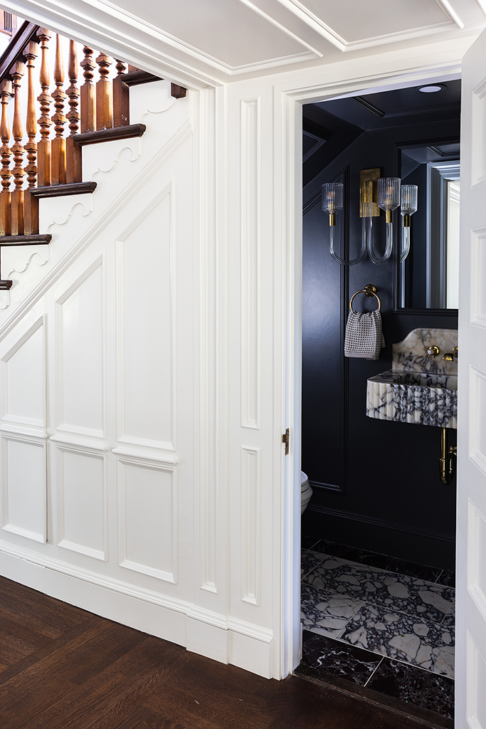 Cleverly designed powder room tucked under the main staircase, utilizing space without sacrificing style.
