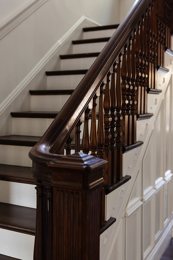 Detailed view of the restored mahogany handrail and newel post on the main staircase.