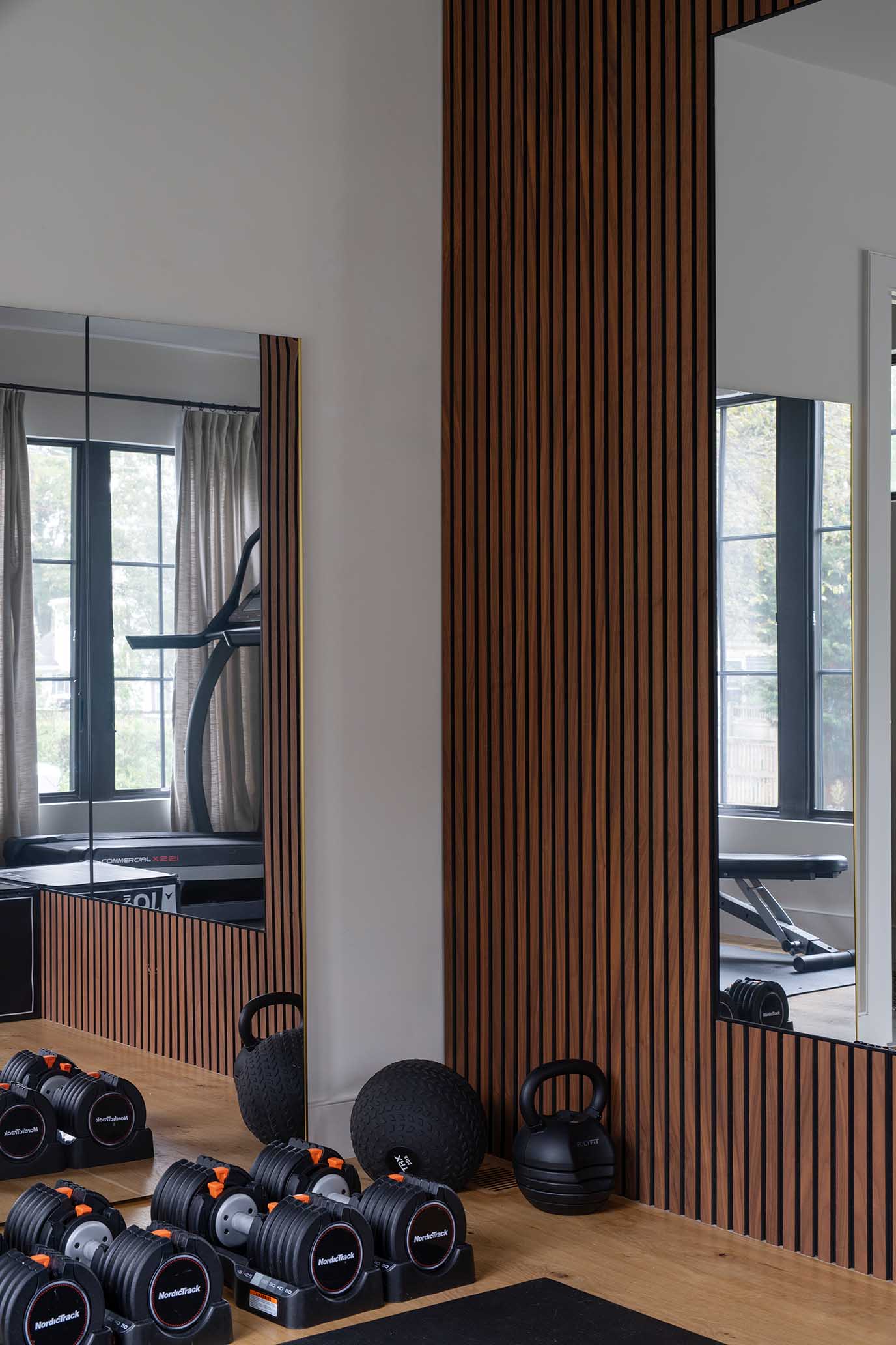 Custom home gym featuring wood slat walls, large mirrors, and wellness amenities, designed by Hill & Harbor in Rhode Island.