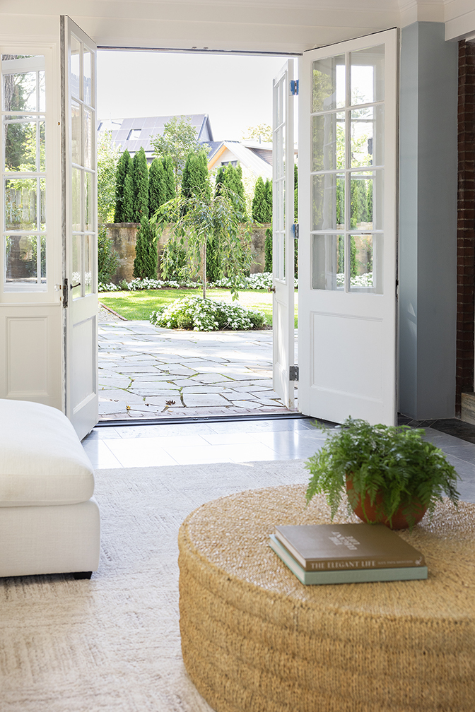 Open French doors connecting the sunroom to the outdoor bluestone patio.