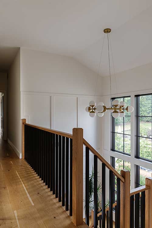 Second-floor hallway view looking down the stairwell, highlighting the clean lines and architectural symmetry.
