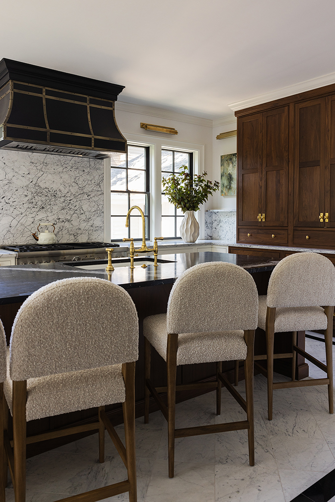 Detail of the kitchen island seating area with upholstered stools and marble countertops.