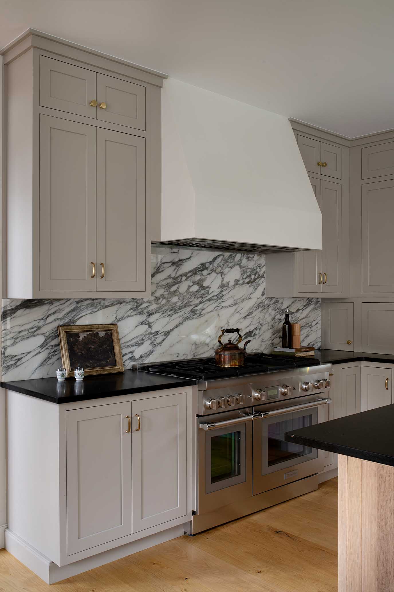 Gourmet kitchen featuring a Wolf range, custom white cabinetry, and marble backsplash in a Rhode Island new construction home.