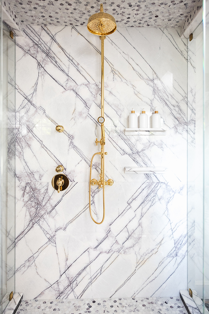 Stunning book-matched marble slab wall in the luxury glass-enclosed shower.