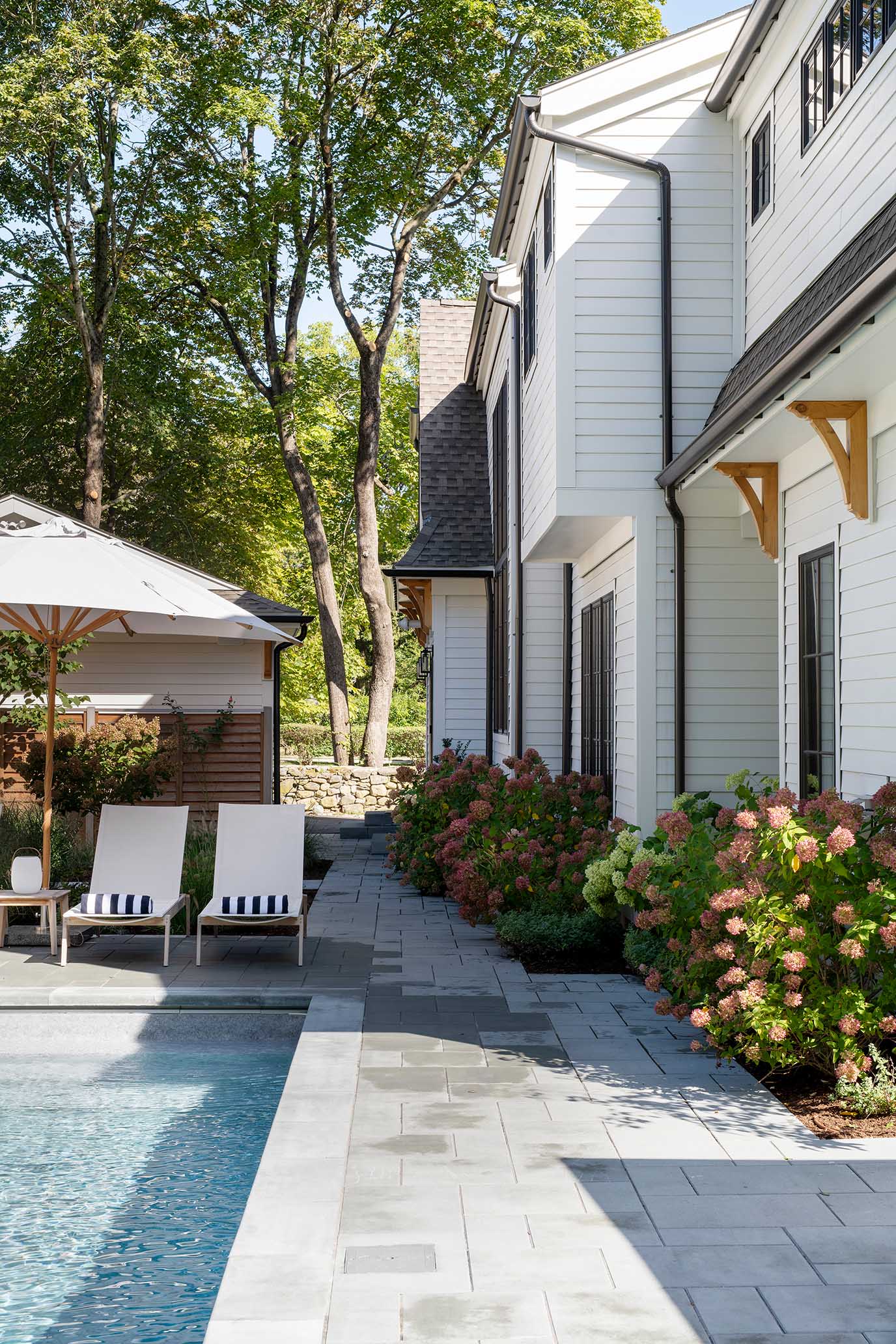 Exterior view of the backyard pool area and white siding, showcasing the seamless transition between indoor and outdoor living in East Greenwich.