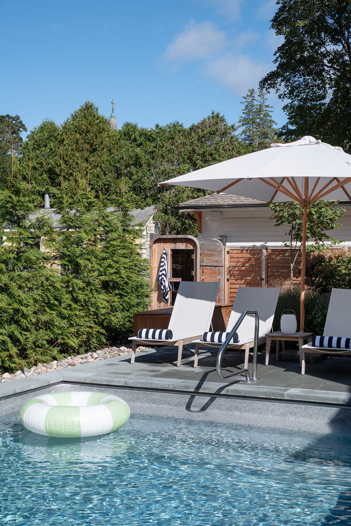 Serene poolside lounge area surrounded by privacy landscaping in a historic East Greenwich neighborhood.