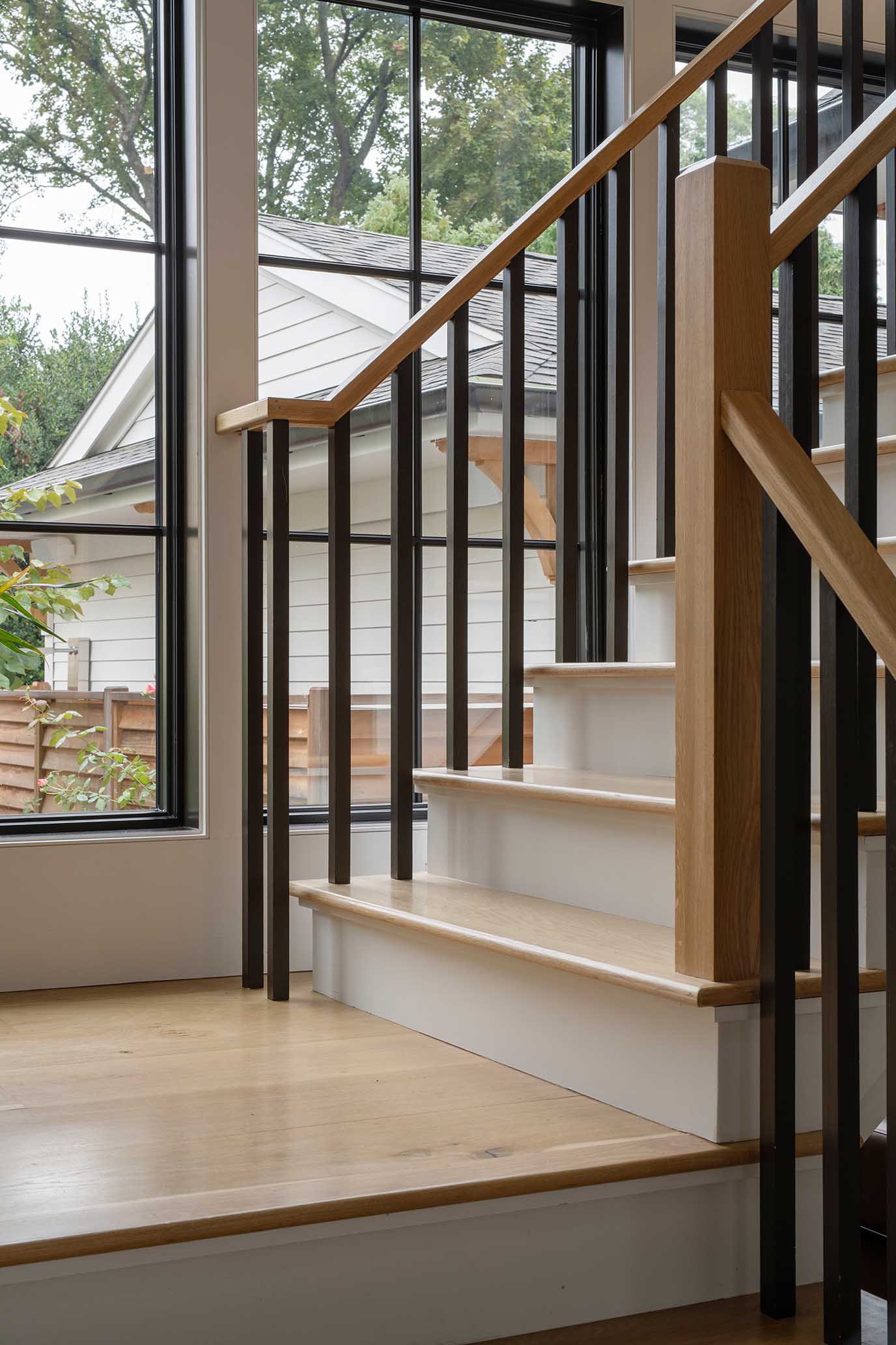 Sunlit stairwell landing with custom white oak treads, reflecting the precise execution of Rhode Island's top general contractors.