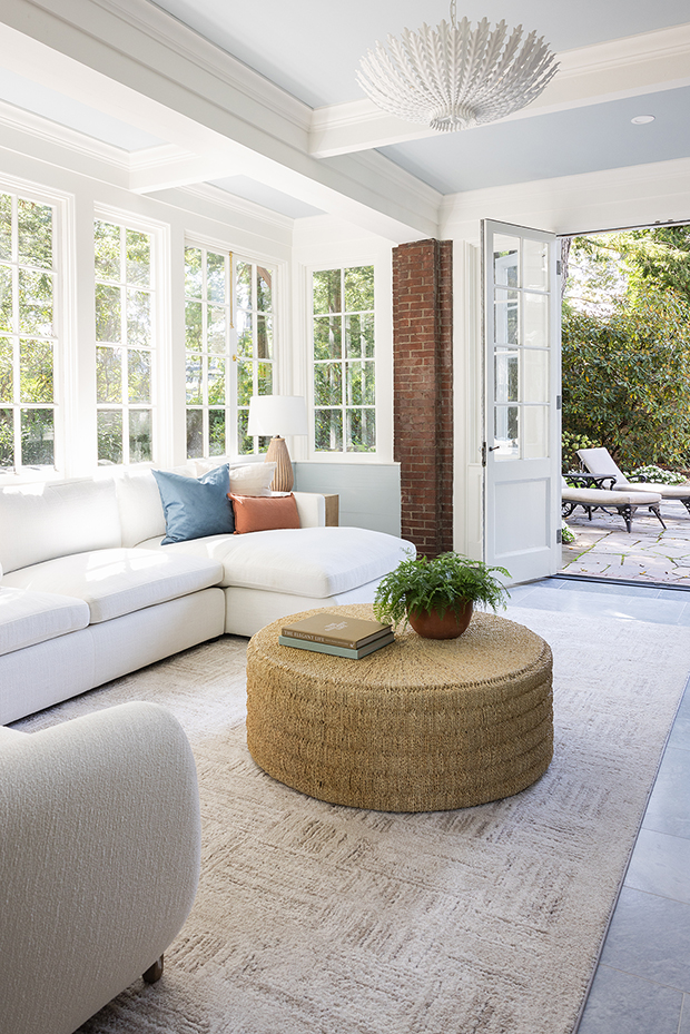 Light-filled sunroom addition with floor-to-ceiling windows and comfortable lounge seating.