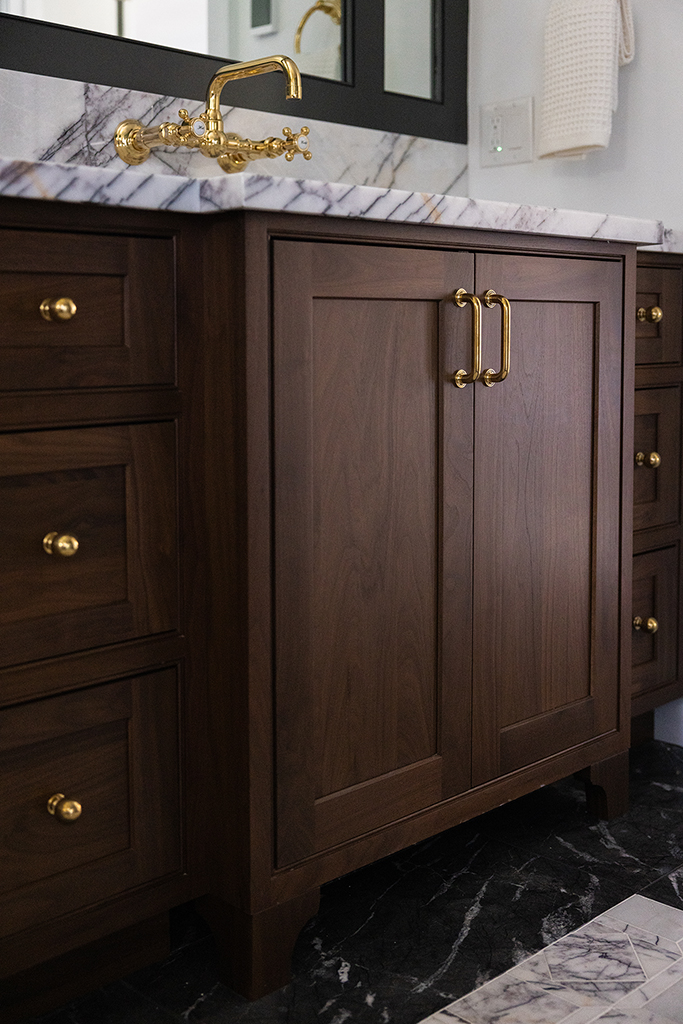 Detail of the custom walnut vanity showing ample storage and high-end brass fixtures.
