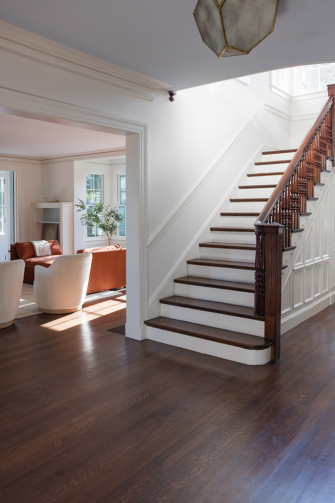 Bright and airy staircase landing featuring refinished white oak floors and classic wainscoting.